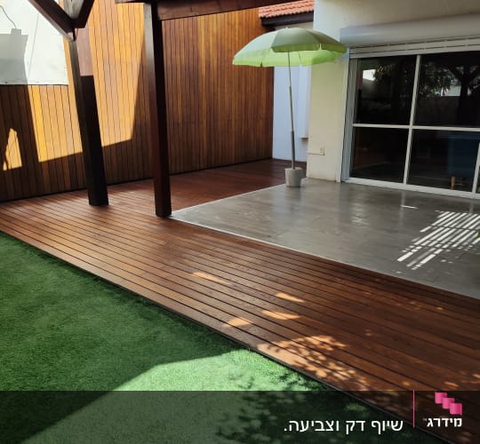 דק עץ עם פרגולה ומטריה ירוקה בגינה